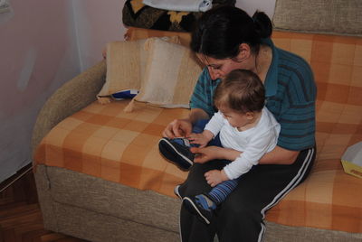 Rear view of boy using mobile phone at home