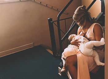 High angle view of woman breastfeeding baby on steps