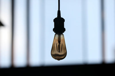 Low angle view of light bulb hanging against wall