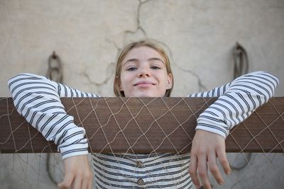 Portrait of girl by fence against wall