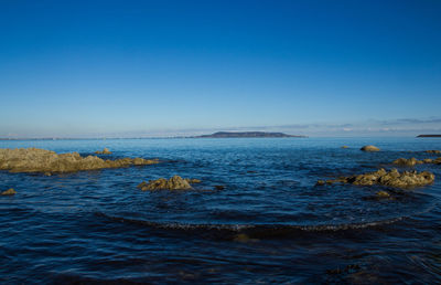 Scenic view of sea against clear blue sky