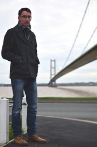 Young man standing by suspension bridge