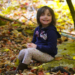 Portrait of smiling girl sitting on autumn leaves