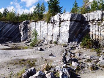 Scenic view of cliff by trees against sky