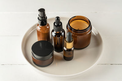 Set of amber glass cosmetic bottles on a plate on wooden background. natural cosmetics unbranded 