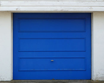 Garage door,cobalt blue on white cement rendered wall