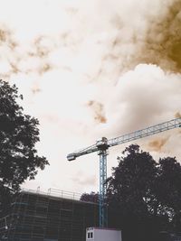 Low angle view of crane against cloudy sky