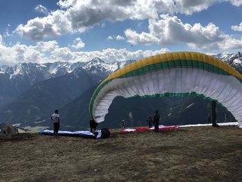 People with parachutes on mountain against sky