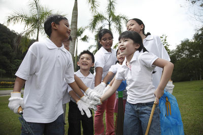 Friends stacking hands while standing against trees