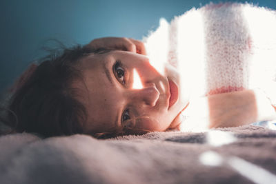 Close-up portrait of young woman lying down