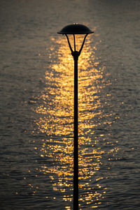 Silhouette pole against sea during sunset