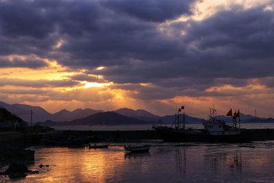 Boats moored at harbor against sky during sunset