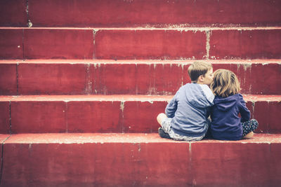 Brother kissing on sister head while sitting over steps