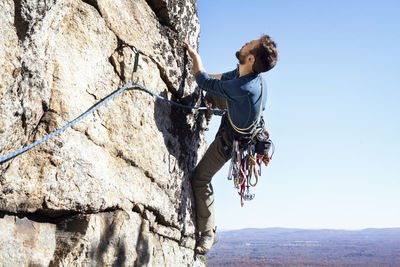 Man rock climbing against clear sky
