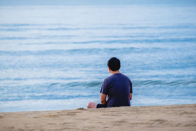 Rear view of man sitting on beach