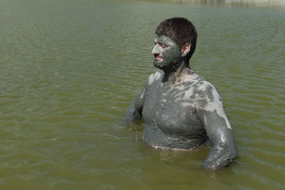 Man with mud on face in lake