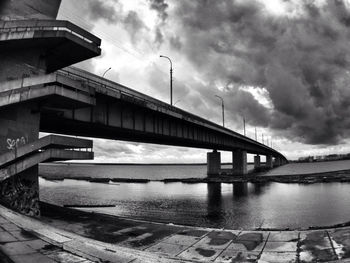 Bridge over river against cloudy sky