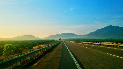 Empty road along landscape against sky