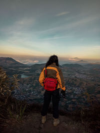 Rear view of man standing on mountain against sky