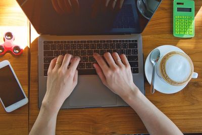 Directly above shot of hand holding coffee cup on table