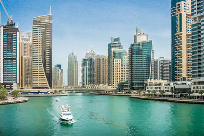 Boats in sea by buildings against sky in city