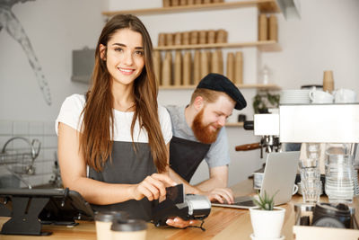 Portrait of smiling young woman standing in kitchen