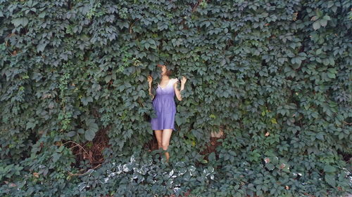 Woman standing by creeper plant