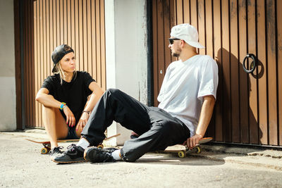 Couple with skateboards sitting in city