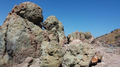 Low angle view of rock formation against clear blue sky