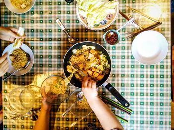 Cropped woman serving noodles on table at home