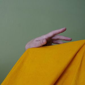 Close-up of woman hand against yellow wall