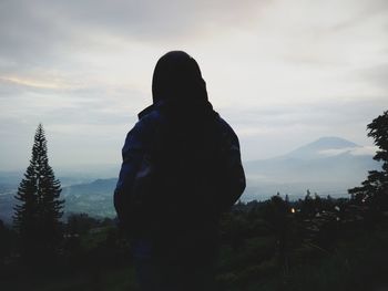 Rear view of silhouette woman standing against sky