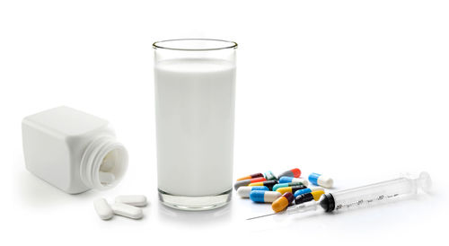 Close-up of medicines with milk on white background
