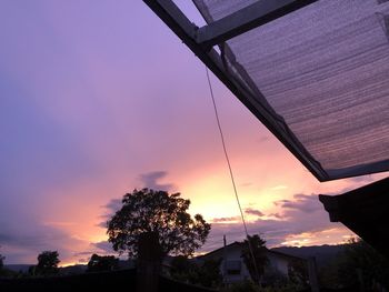 Low angle view of silhouette trees and buildings against sky during sunset