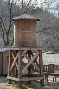Wooden log cabin by trees in forest during winter