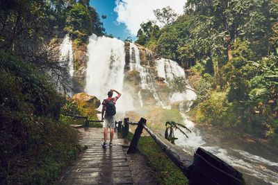 Rear view of young man against waterfall