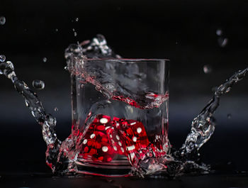 Close-up of water splashing on glass against black background