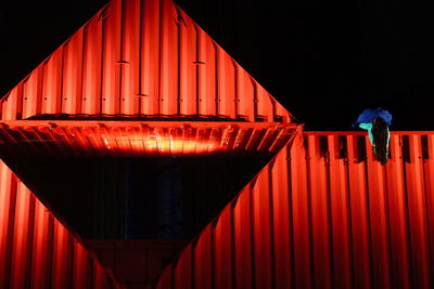 Man standing in red illuminated at night