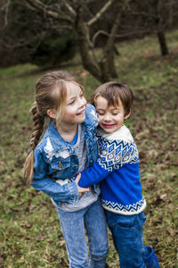 Siblings standing on field