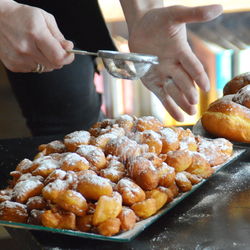 Cropped image of woman sprinkling powdered sugar on dessert