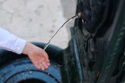 Cropped hand of person holding water falling from fountain