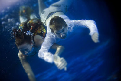 Friends swimming underwater in pool