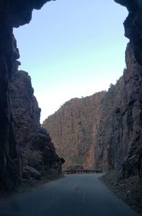 Road leading towards mountains against clear sky