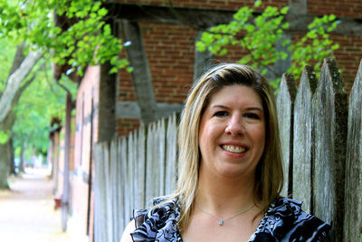 Portrait of smiling mature woman standing by fence