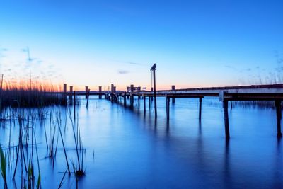 Scenic view of wooden posts against sky at sunset