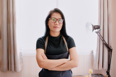 Portrait of young woman standing against wall
