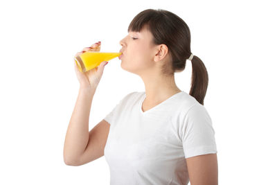 Young woman drinking glass against white background