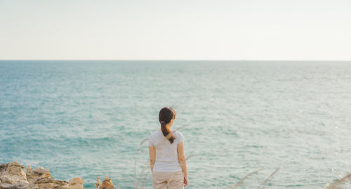 Rear view of woman looking at sea against clear sky