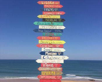 Information sign on beach against clear sky