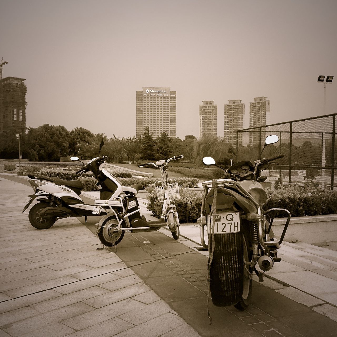 bicycle, building exterior, land vehicle, transportation, mode of transport, architecture, built structure, parked, stationary, parking, city, street, clear sky, parking lot, road, day, outdoors, car, sidewalk, sunlight